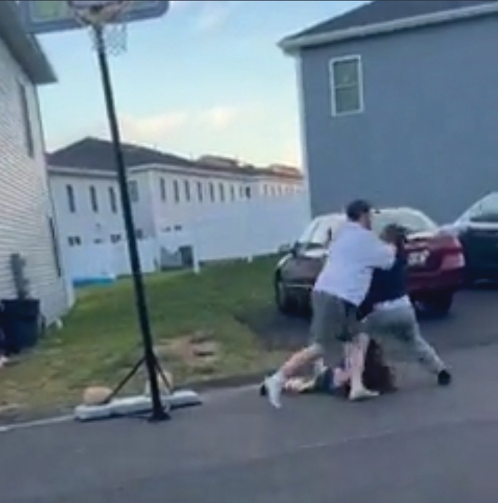 In the video, two children start fighting underneath a basketball hoop. Eventually, as one child gains the advantage, an adult male who was watching the fight, jumps into the brawl and tackles one of the children, falling on the street. The video posted on social media ends immediately after. 